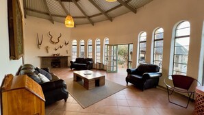 Ein geräumiges Wohnzimmer mit Kamin, Ledersofas, einem Couchtisch und einem großen Fenster mit Rundbögen.