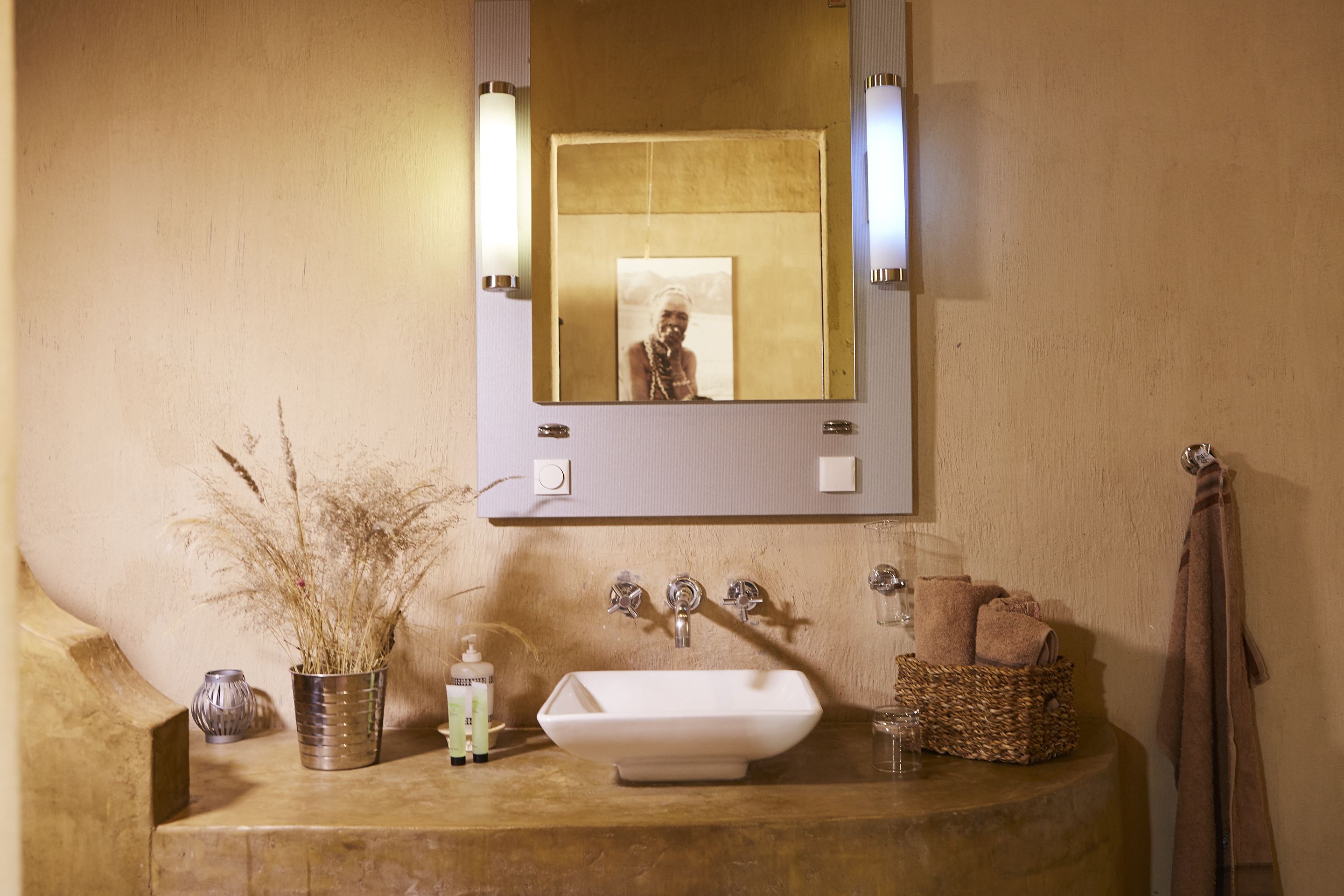 Un baño con lavamanos, espejo y perchero para toallas.