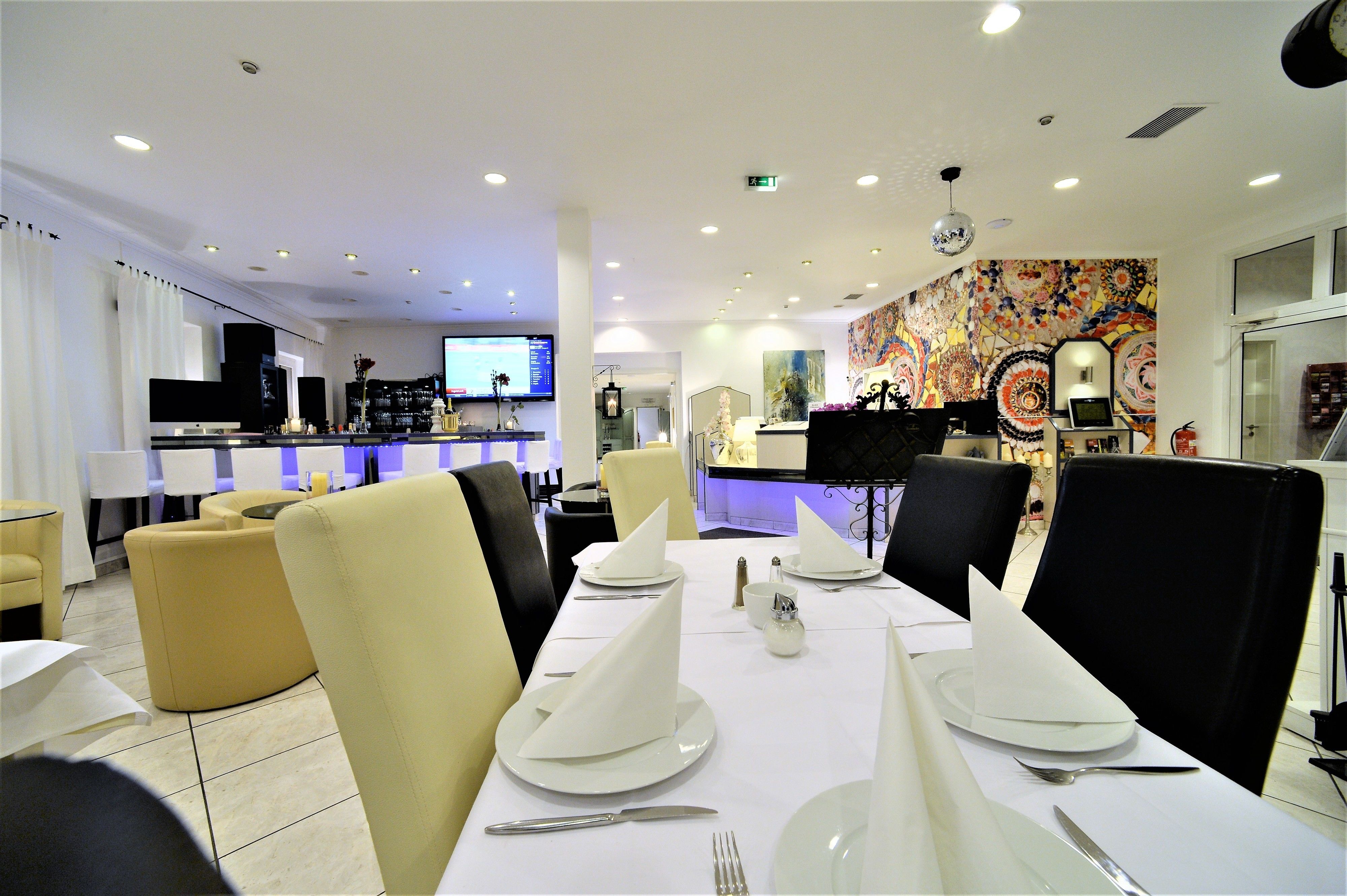 Un restaurante con una larga mesa dispuesta para comer, sillas y una zona de bar al fondo.
