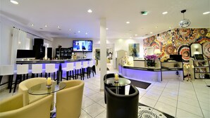 A hotel lobby with a bar area, seating, and a colorful wall mural. - Ascot Hotel (Remscheid)