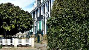A historic building with a cobblestone pathway leading to a white picket fence. - Ascot Hotel (Remscheid)