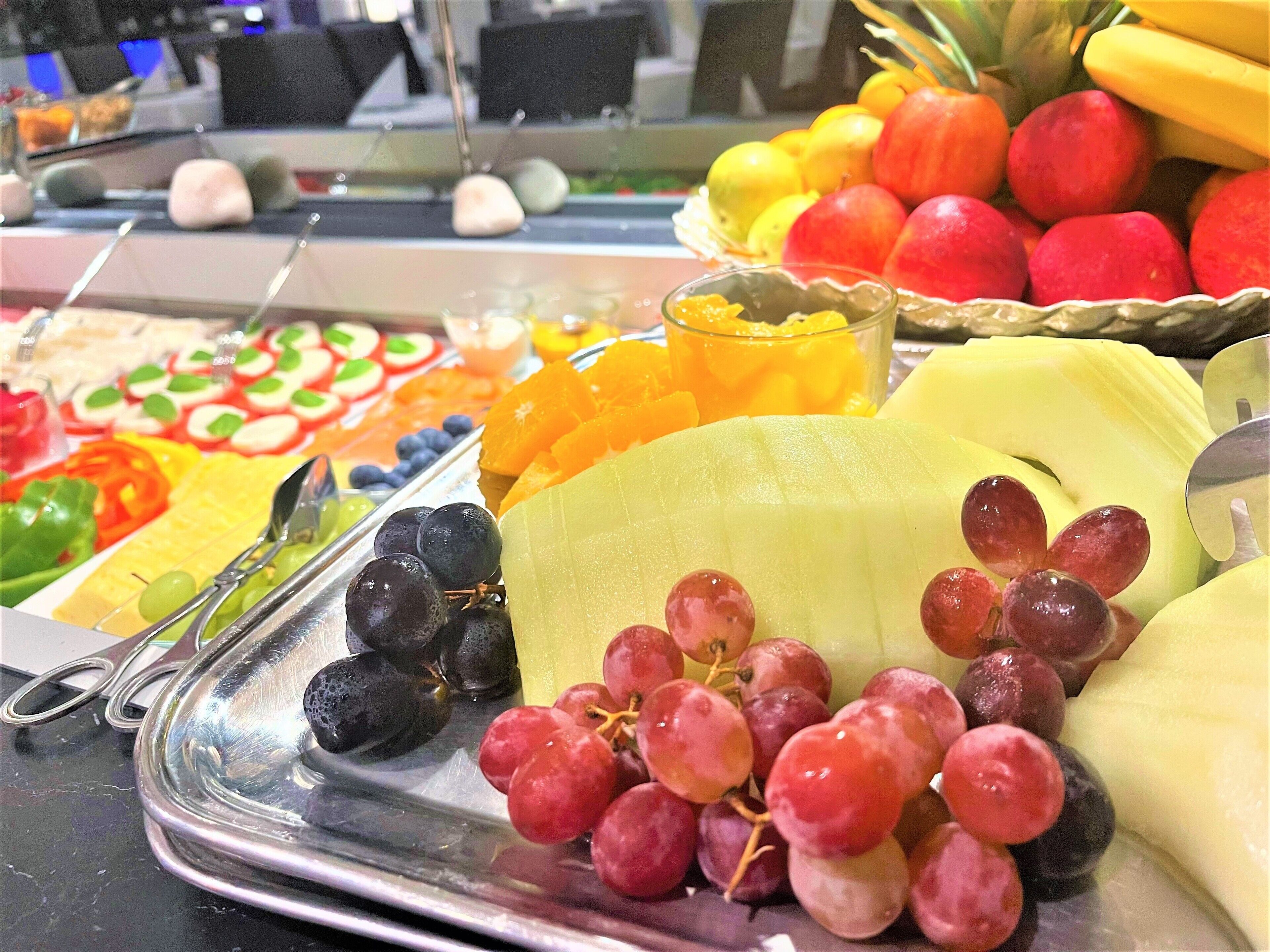A buffet with a variety of fruits and vegetables, including grapes, apples, and oranges.