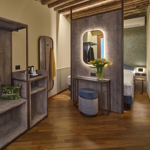 A modern bathroom with a wooden vanity, a mirror, a sink, and a toilet. There is a small stool and a vase with flowers on the vanity. - Residenza Favaro (Venice)