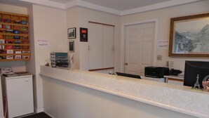 A reception area with a counter, a refrigerator, a door with a number, and a framed picture on the wall.