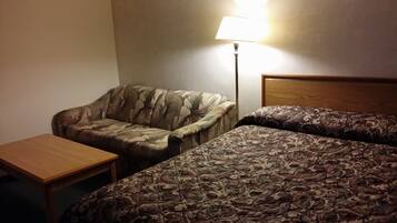 A hotel room with a single bed, a small table, a chair, and a lamp.