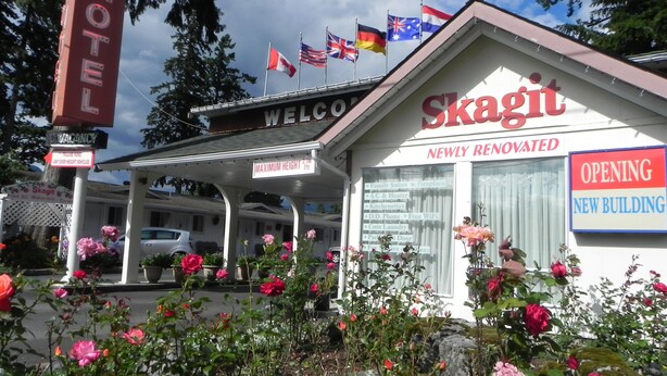 A motel named Skagit with a 'Welcome' sign, flags, and a newly renovated building.