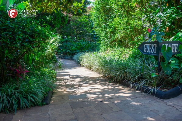 A pathway surrounded by lush greenery, leading to signs labeled 'GUEST' and 'STAFF'. - Fairway Hotel & Spa (Kampala)