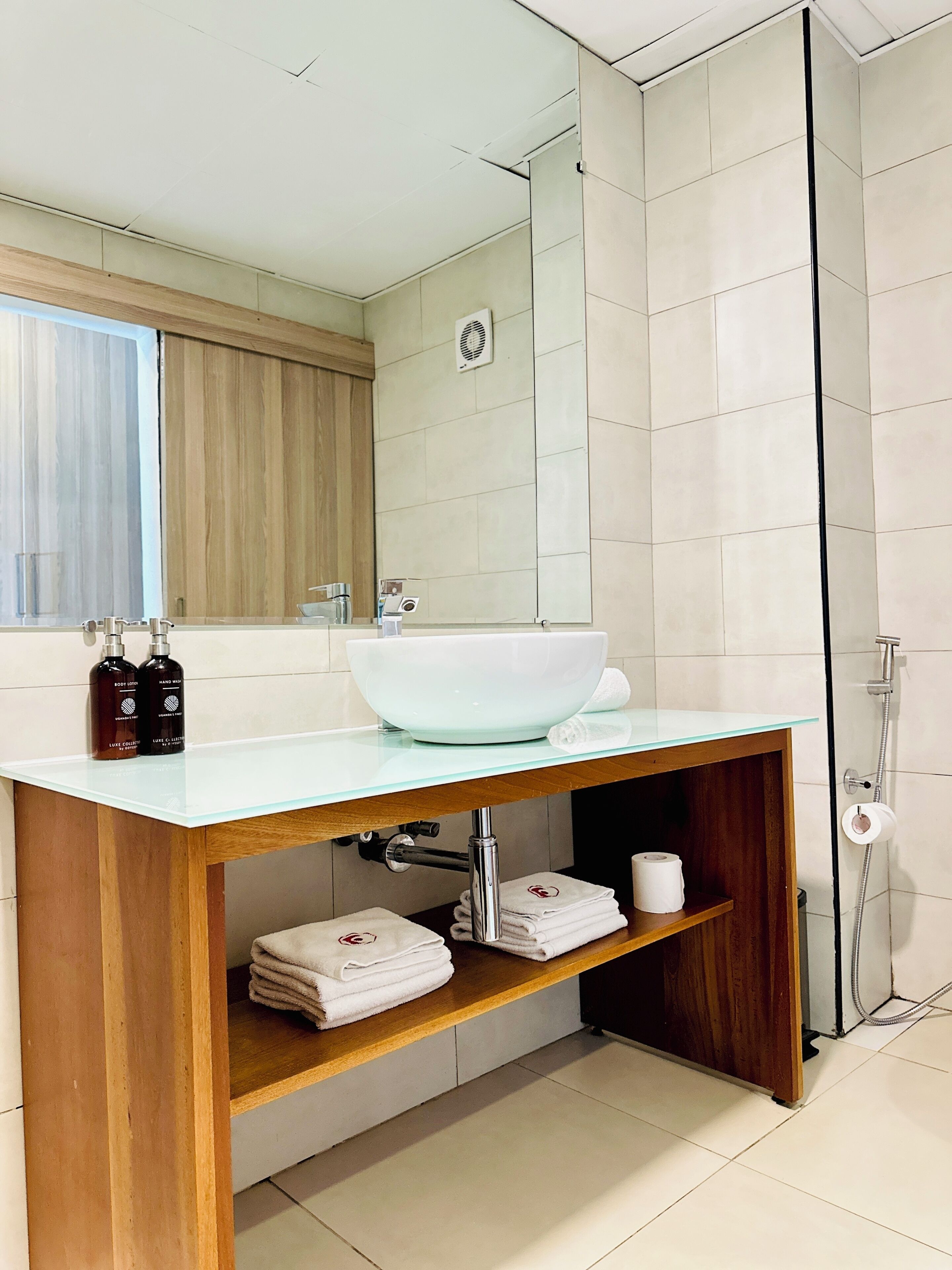 Un baño moderno con un lavamanos grande blanco, tocador de madera y cabina de ducha con mampara de vidrio.