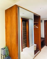 Un armario moderno con puerta espejo corredera, una barra para colgar ropa y una pequeña planta.
