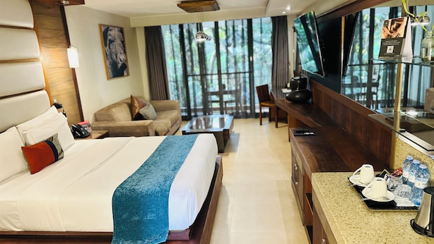 A hotel room with a large bed, a TV, a desk with a coffee maker, and a view of the outdoors. - Fairway Hotel & Spa (Kampala)