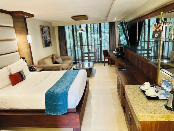 A hotel room with a large bed, a TV, a desk with a coffee maker, and a view of the outdoors. - Fairway Hotel & Spa (Kampala)