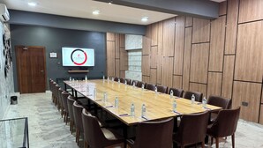 A conference room with a long table, chairs, water bottles, and a projector screen. - Fairway Hotel & Spa (Kampala)