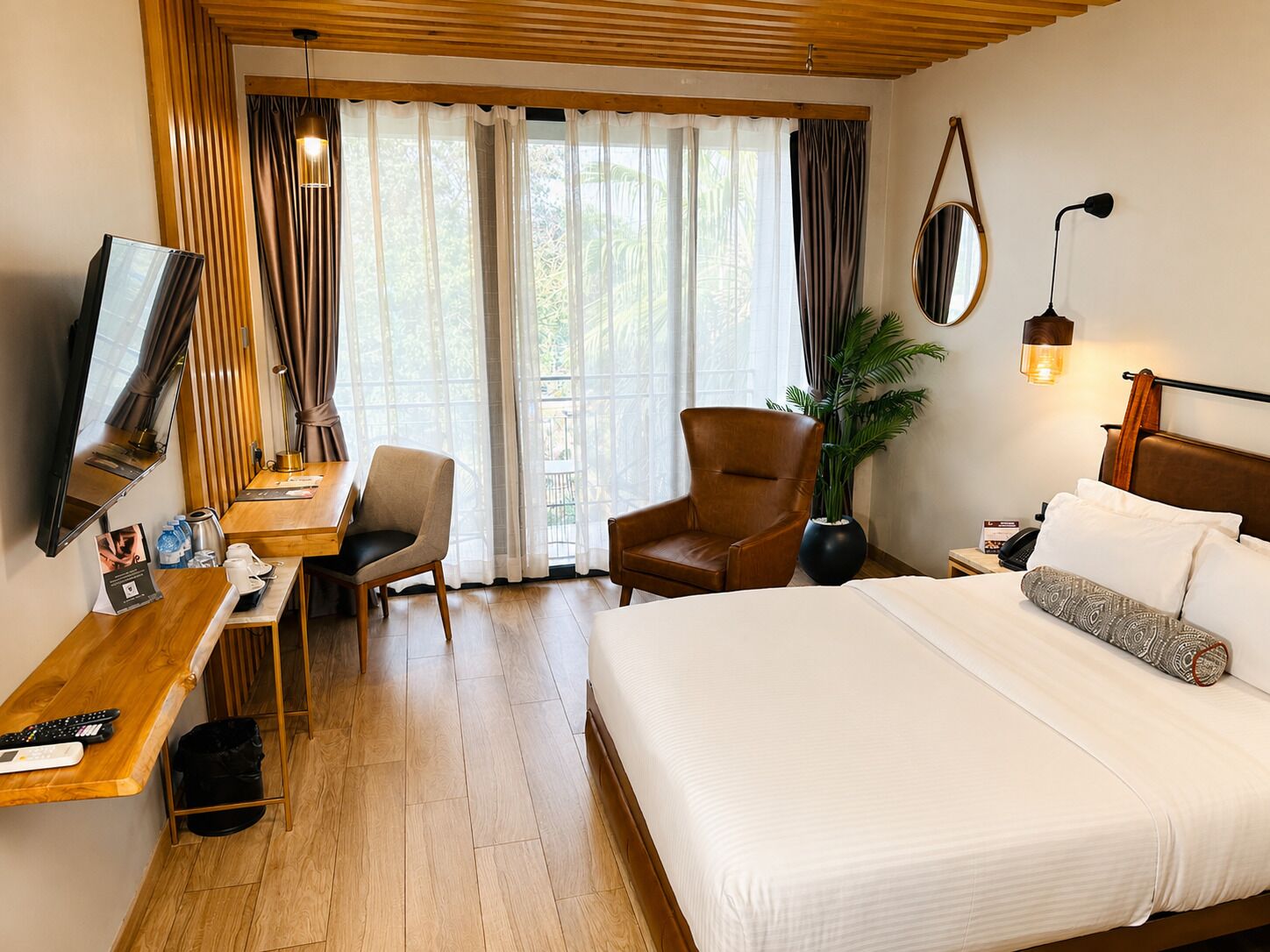 A hotel room with a bed, desk, chair, TV, and a large window with curtains.