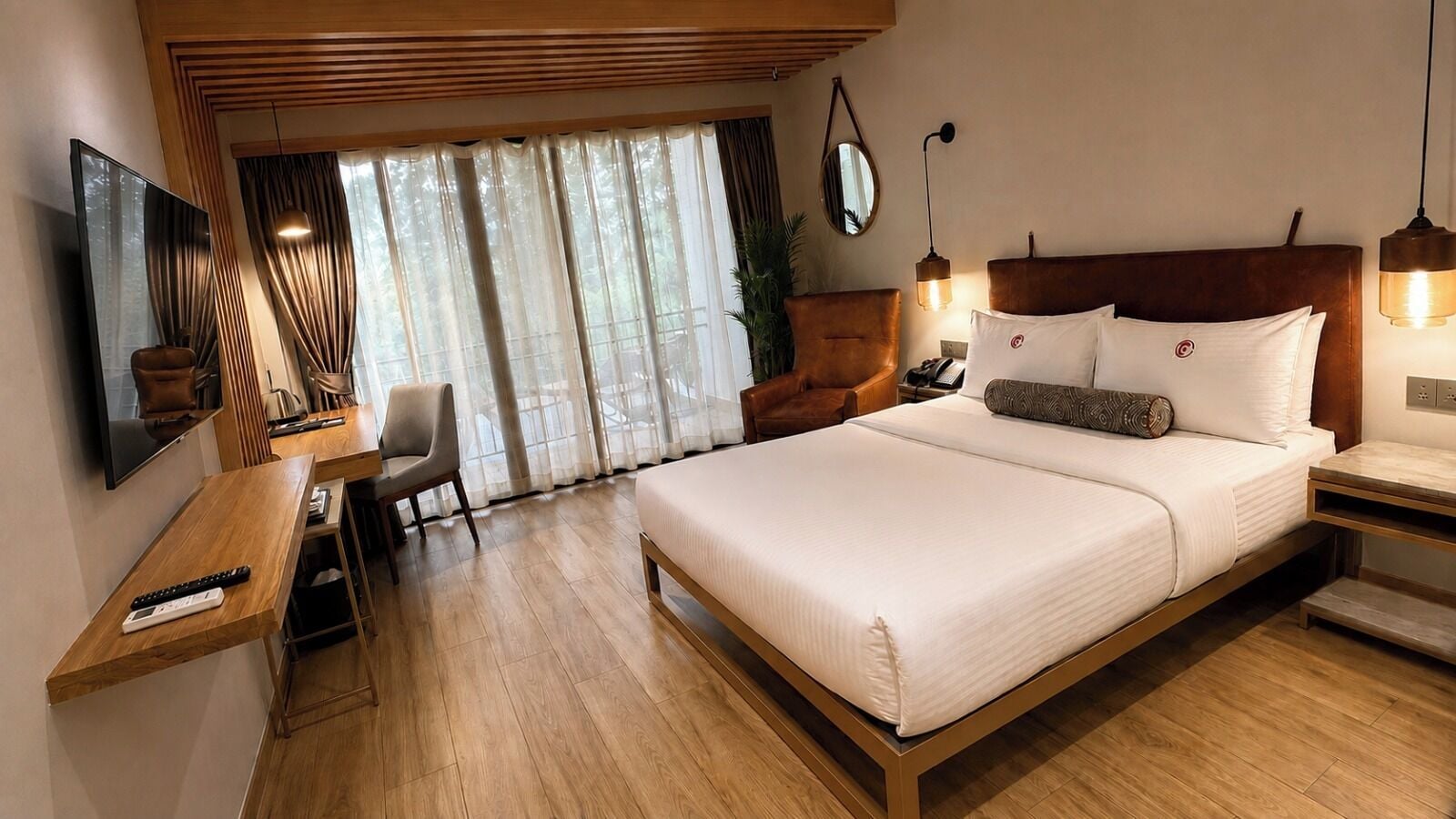 A hotel room with a bed, bedside table, lamp, chair, and a TV mounted on the wall.