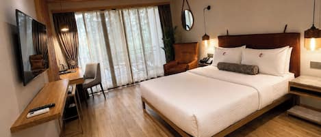 A hotel room with a bed, bedside table, lamp, chair, and a TV mounted on the wall.