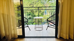 A balcony with a table and two chairs, a view of greenery, and a building in the background. - Fairway Hotel & Spa (Kampala)