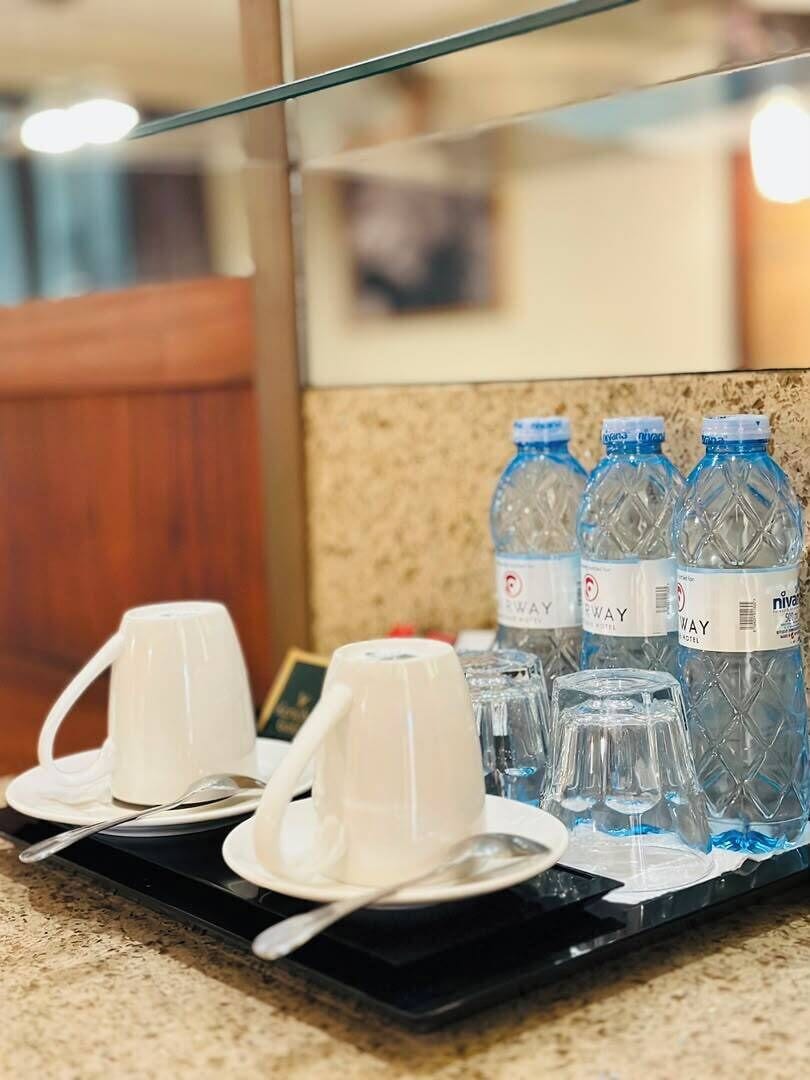 Un plateau avec des tasses, des soucoupes et des cuillères blanches, ainsi que plusieurs bouteilles d’eau portant des étiquettes.