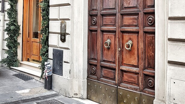 A large wooden door with a metal grill, a smaller wooden door with a green wreath, and a mailbox on the wall. - Relais Cavour Inn (Rome)