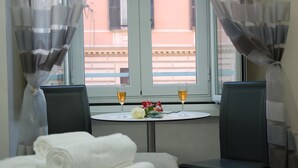 A hotel room with a bed, two chairs, a small table with two glasses of wine and a bouquet of flowers, and a window with curtains. - Relais Cavour Inn (Rome)