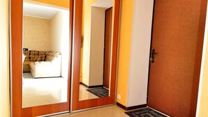 Un corridoio con una porta in legno, un armadio specchiato e un pavimento piastrellato.