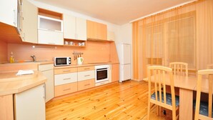 Una cucina compatta con mobili in legno, un forno a microonde, un forno e un angolo ristoro con tavolo e sedie.