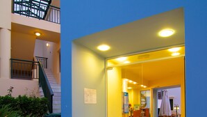 A hotel lobby with a blue exterior, a staircase to an upper floor, and a reception desk. - Radamanthy's Apartments (Rethymno)