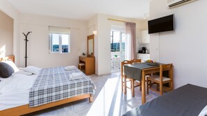 A bedroom with a bed, a desk, a chair, a television, and a balcony with a view. - Radamanthy's Apartments (Rethymno)