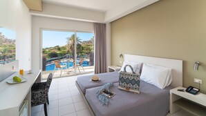 A hotel room with a bed, a desk with a chair, a phone, and a view of a swimming pool and hills. - Cathrin Hotel Rhodes By Anayia All Inclusive Resorts (Rhodes)