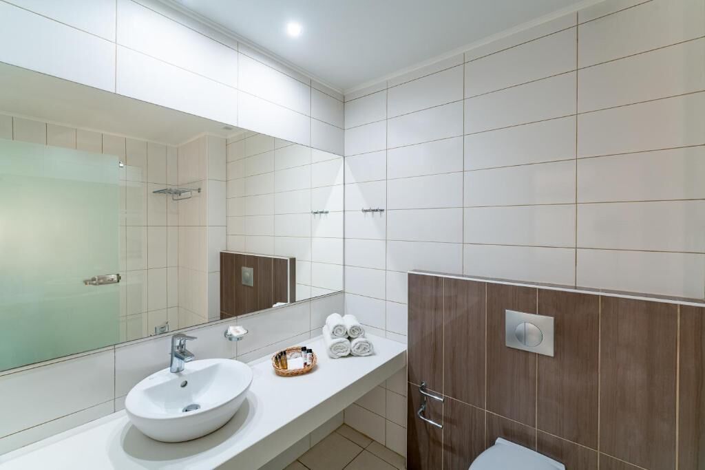 A modern bathroom with a white sink, a large mirror, and a shower area.