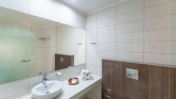 A modern bathroom with a white sink, a large mirror, and a shower area.