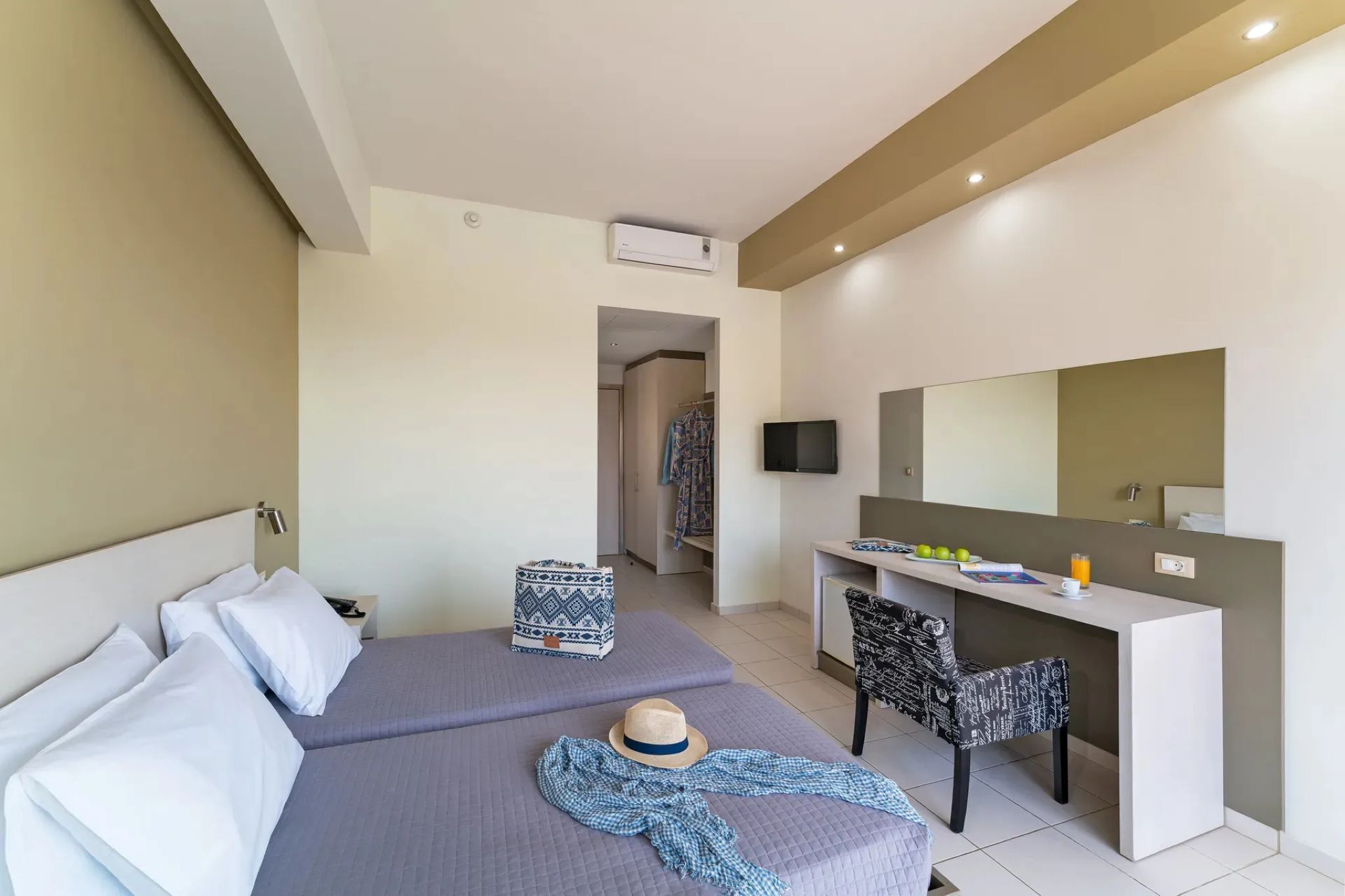 Une chambre d’hôtel avec deux lits, un bureau, une chaise, une télévision et un miroir.