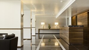 Un hall d’entrée moderne avec un comptoir d’accueil, un canapé et un mur décoratif en bois.