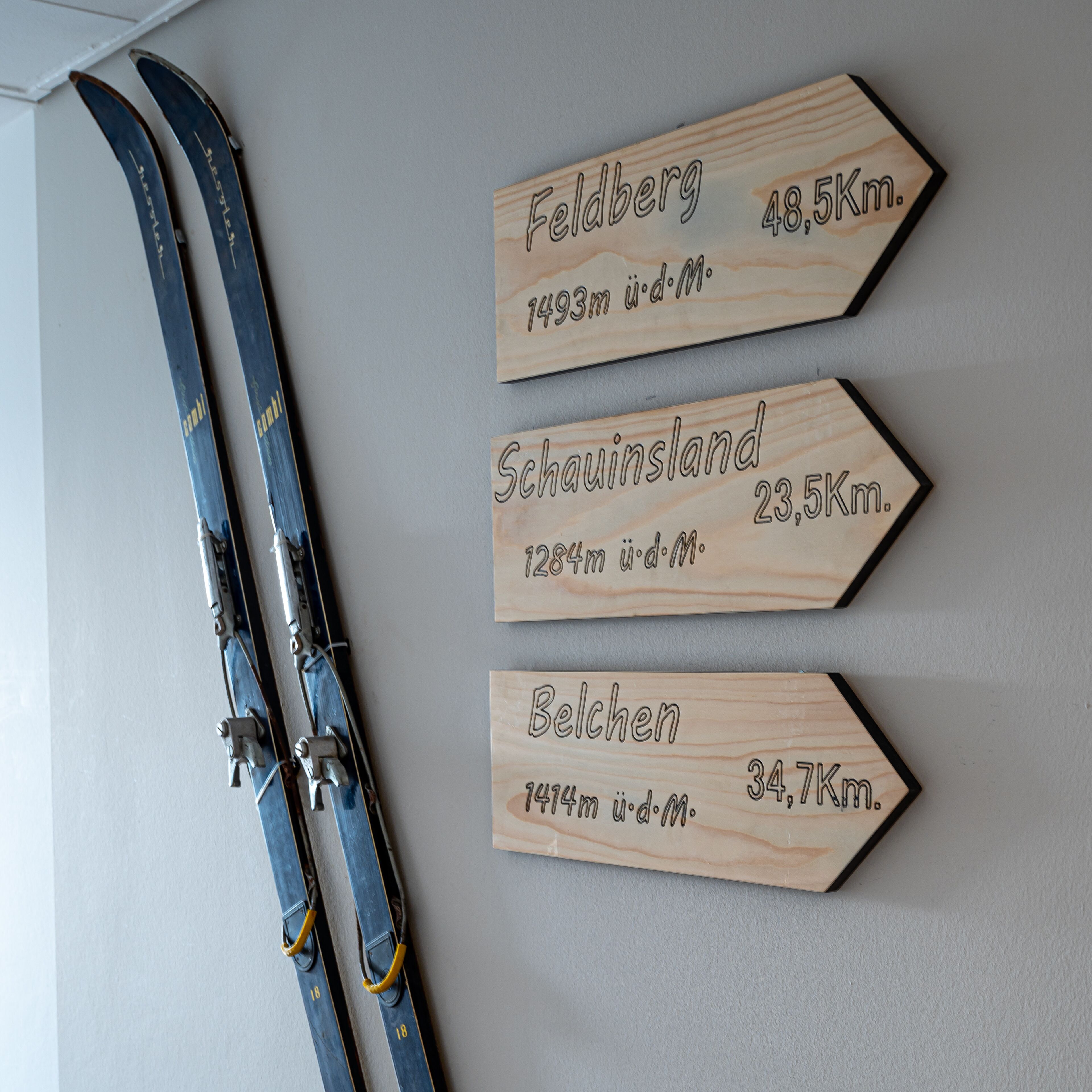 Three wooden signs with distances and elevations, mounted on a wall.