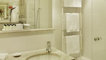 A modern bathroom with a granite sink, a large mirror, and a glass shower enclosure.