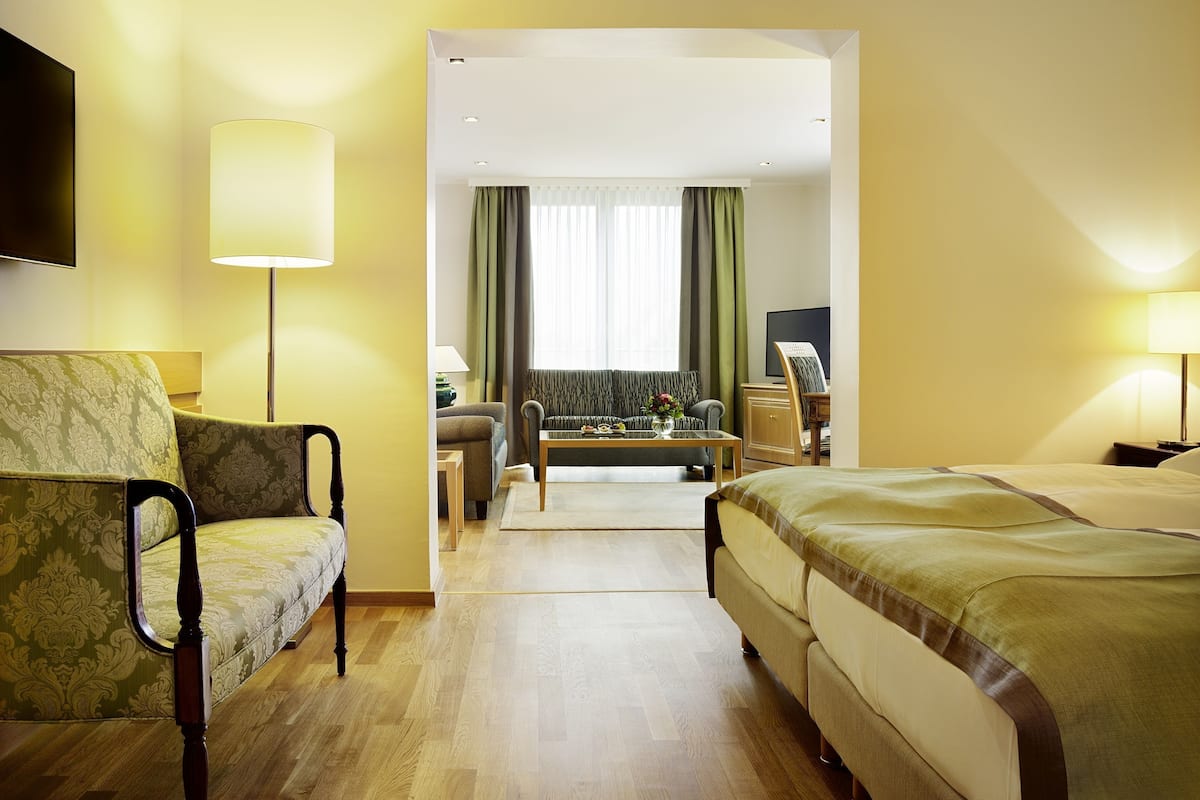 Une chambre d’hôtel avec un lit, une chaise, un bureau, une télévision et une fenêtre avec des rideaux.