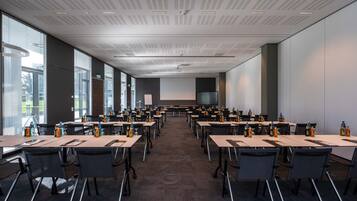 Un salón de conferencias con varias mesas y sillas, equipado con botellas de agua y tarjetas de identificación.