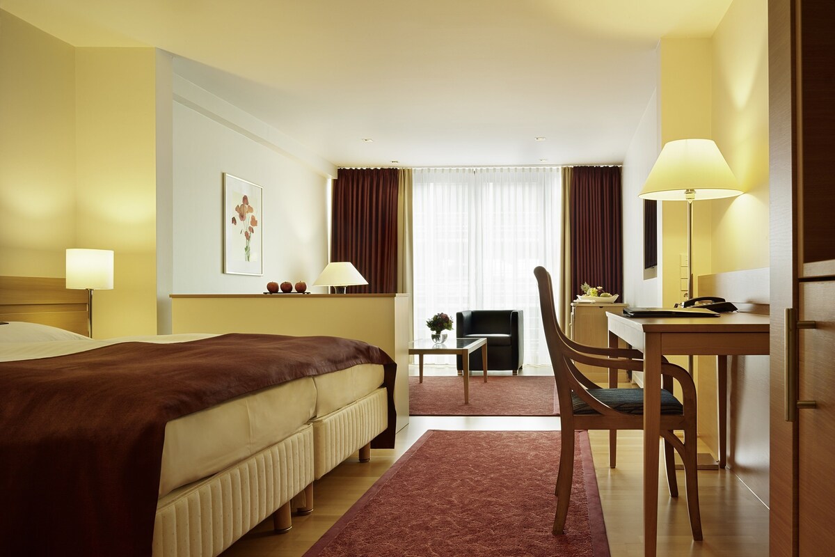 Een hotelkamer met een bed, bureau, stoel en uitzicht op de omgeving.