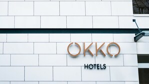 Fachada de un edificio con diseño moderno, con un letrero que dice 'OKKO HOTELS'.