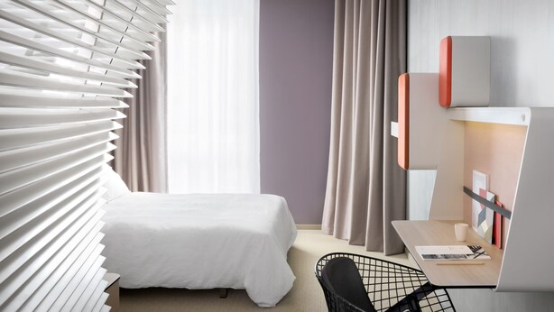 Una habitación de hotel con una cama, un escritorio y una silla.