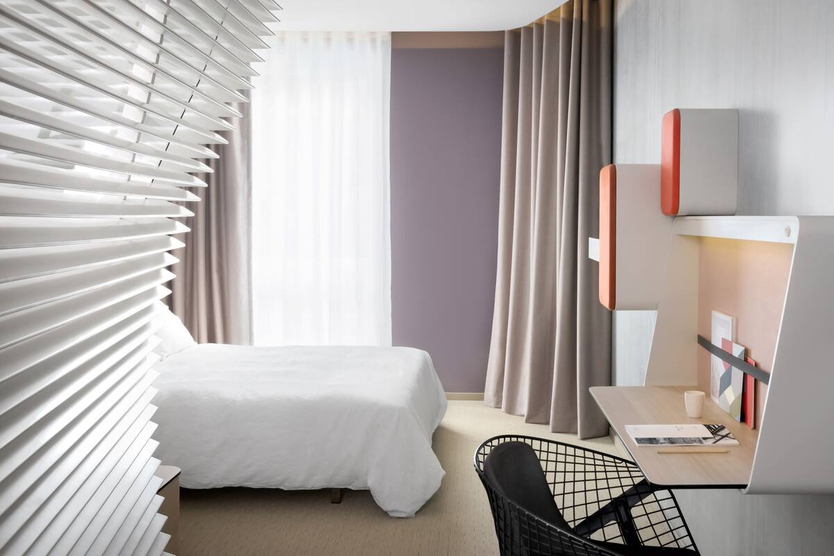 Una habitación de hotel con una cama, un escritorio y una silla.