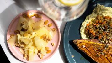 Un plato de comida con rodajas de manzana y nueces, y otro plato con batata horneada cubierta de hierbas.