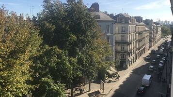 Une vue de rue avec des voitures garées, des arbres et des bâtiments.