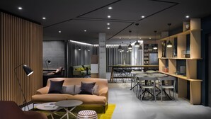 Una sala moderna con sofá, mesa de centro y lámpara. Hay un comedor con mesa y sillas. La habitación tiene un diseño contemporáneo con detalles de madera y una pared estampada.