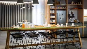 Una cocina moderna con una isla central, taburetes de bar, iluminación colgante y una variedad de electrodomésticos y estanterías.