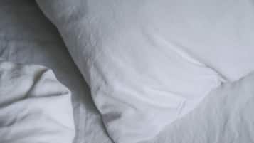 Primer plano de una cama con ropa de cama blanca.