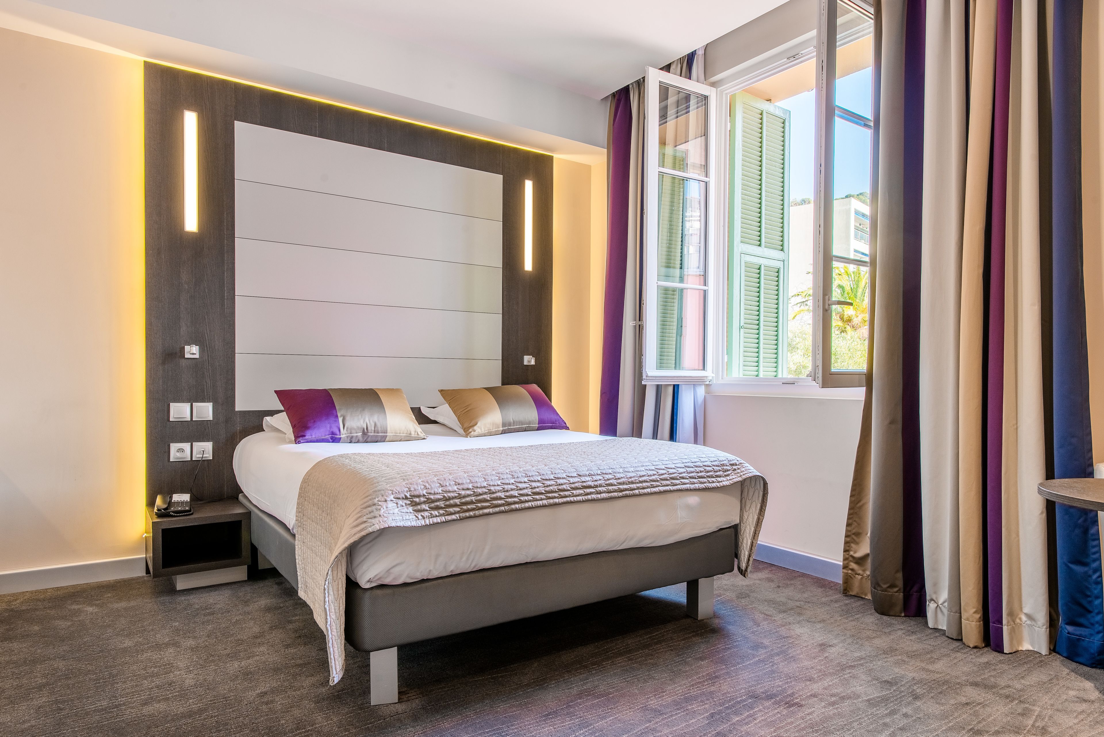 A modern bedroom with a bed, bedside tables, and a window with curtains.