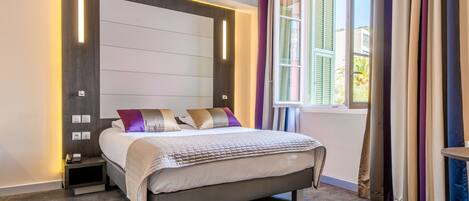 A modern bedroom with a bed, bedside tables, and a window with curtains.