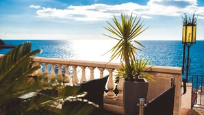 A balcony with a view of the sea, a potted plant, and a street lamp. - Le Saint Paul Hôtel (Nice)