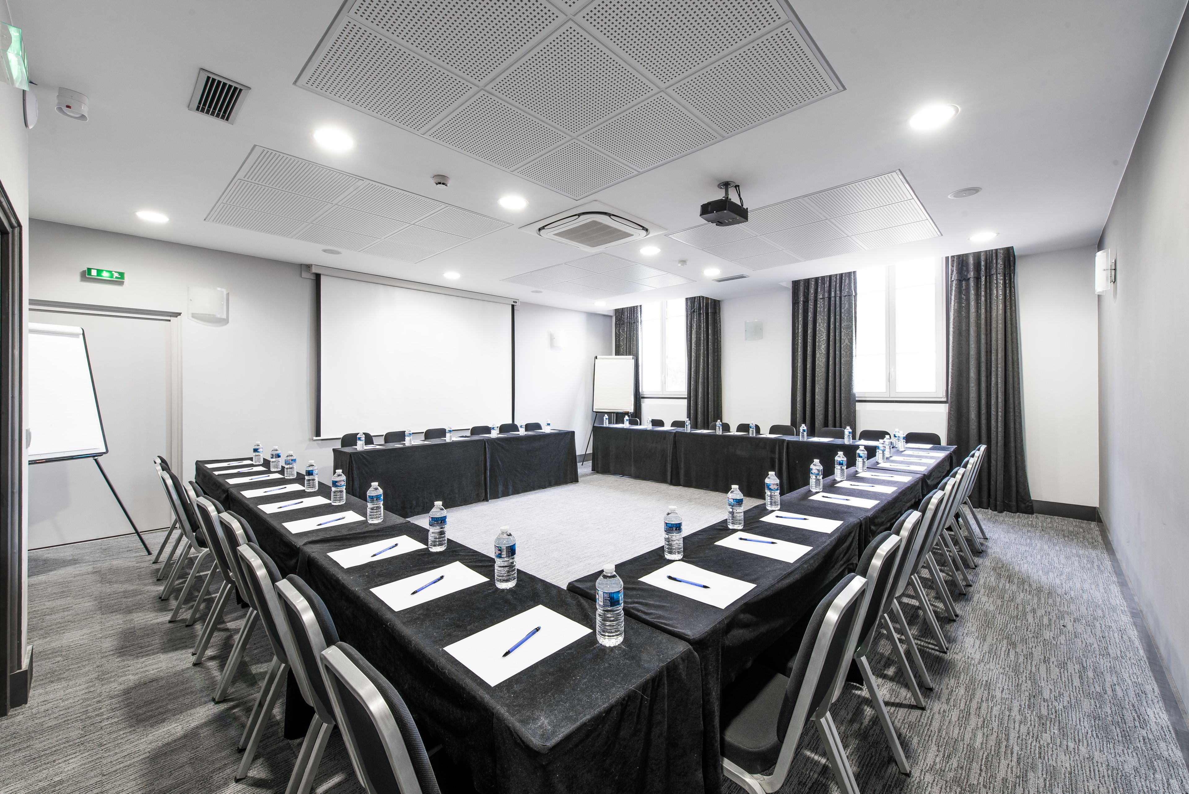 A conference room with a long table, chairs, water bottles, and a projector.