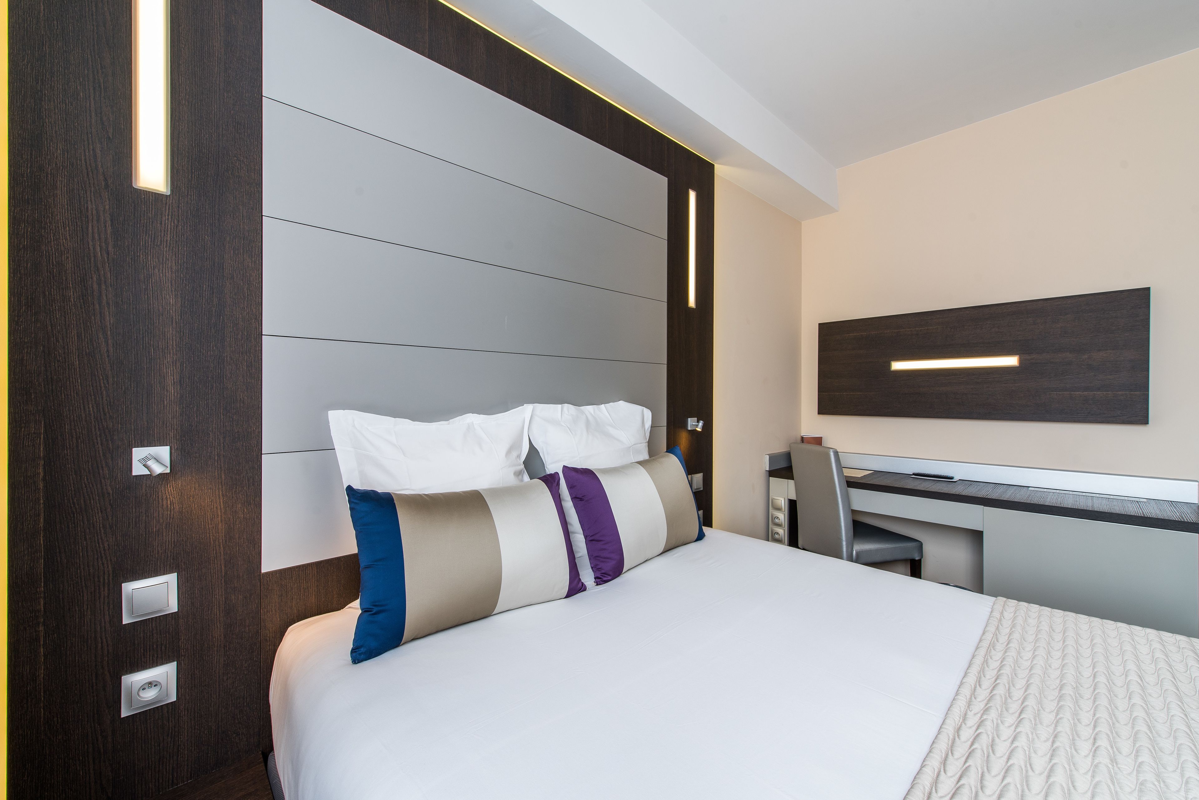 Ein modernes Hotelzimmer mit einem großen Bett, einem Schreibtisch und einem wandmontierten Flachbildfernseher.
